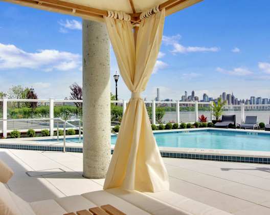 A poolside lounge chair with a yellow draped canopy.