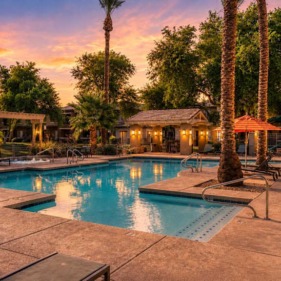 A pool surrounded by palm trees and lounge chairs.