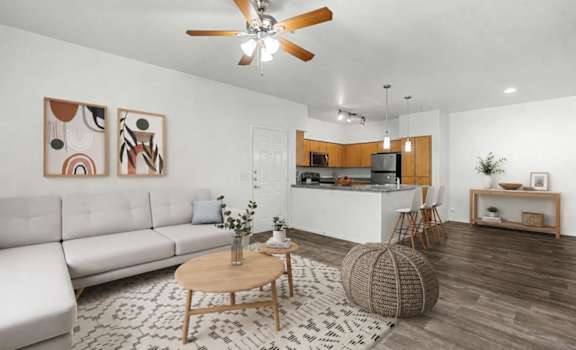 A living room with a white sofa, a wooden coffee table, and a ceiling fan.