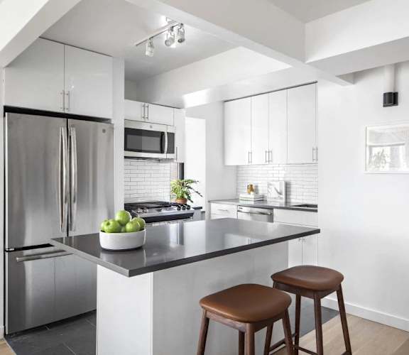 A modern kitchen with a stainless steel refrigerator and a black countertop.