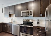 Thumbnail 4 of 11 - a kitchen with dark wood cabinets and stainless steel appliances