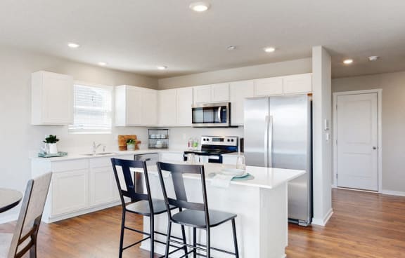 a kitchen with a large island and a stainless steel refrigerator