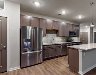 This 2 bedroom Hibiscus floor plan at WH Flats features an open kitchen with neutral gray cabinets, light granite countertops, stainless steel appliances, and white trim.