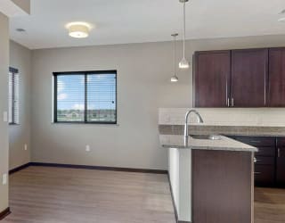 The 2 bedroom Snowdrop with den floor plan at WH Flats features an open eat-in kitchen area with granite countertops and large peninsula.
