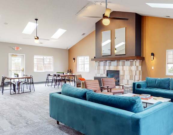 Spacious clubhouse with vaulted ceiling, natural light, fireplace and sitting areas at the Northbrook Apartments