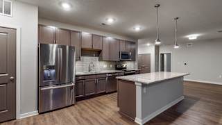 This 2 bedroom Hibiscus floor plan at WH Flats features an open kitchen with neutral gray cabinets, light granite countertops, stainless steel appliances, and white trim.