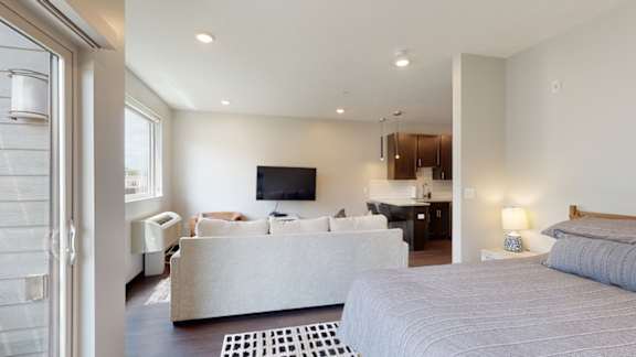 a studio apartment with a bed and a couch in front of a tv