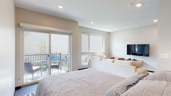 a studio apartment with a large bed and a tv on the wall