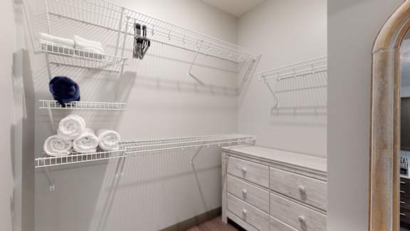 a large walk in closet with a large mirror and a dresser