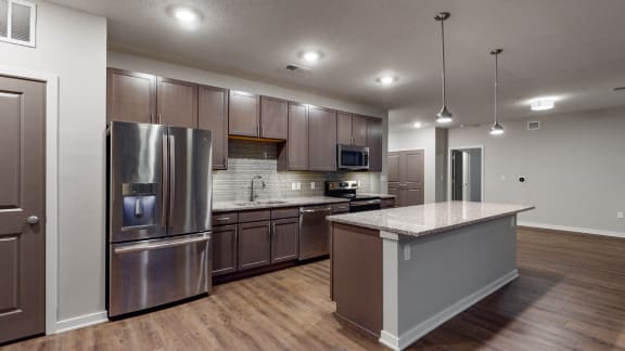 This 2 bedroom Hibiscus floor plan at WH Flats features an open kitchen with neutral gray cabinets, light granite countertops, stainless steel appliances, and white trim.