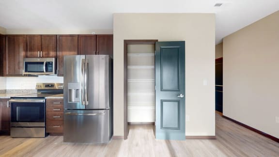 This 2 bedroom Snowdrop with den floor plan at WH Flats features an open kitchen with dark cabinets, granite countertops, and a large pantry.