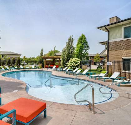Organically shaped resort style pool surrounded a pool deck with bright blue lounge chairs