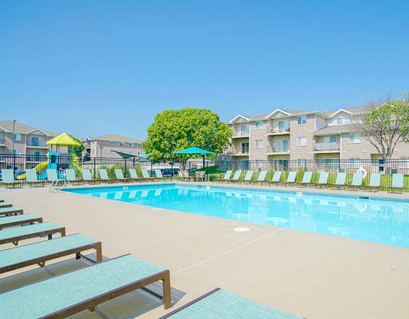 Outdoor pool with lounge beside a playground in Highland View.