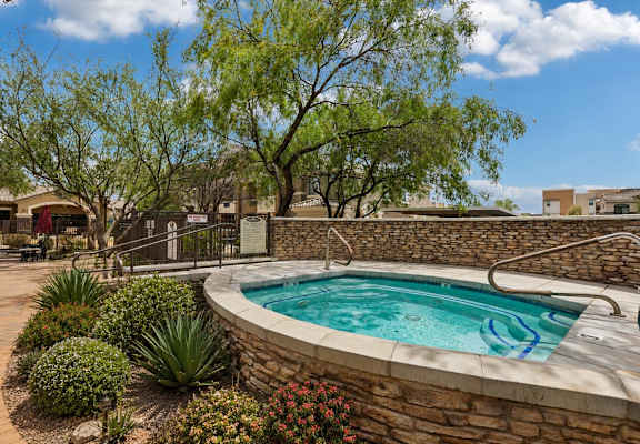 A small pool surrounded by a stone wall and landscaping.