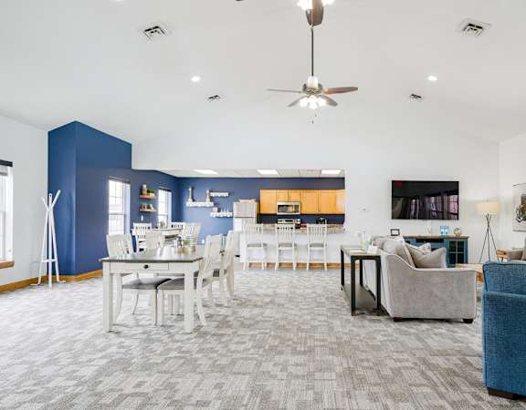 lounge and dining area of a clubhouse with blue walls and white furniture