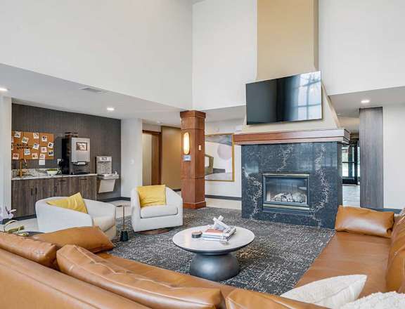 The clubhouse lounge featuring a 2-way fireplace, coffee bar, tv, and lounge seating.