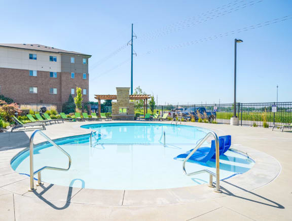 a swimming pool with blue chairs and a building in the background