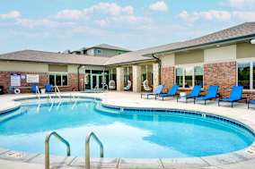 A swimming pool with blue chairs and a building in the background.