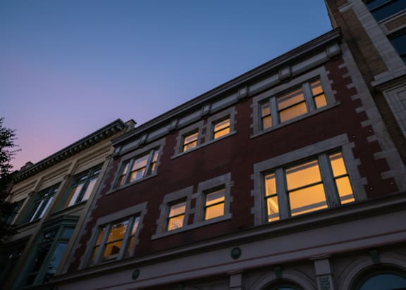 A row of buildings with lit windows at dusk.