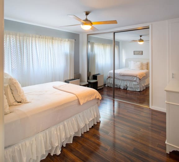 A bedroom with a large bed and a mirrored closet door.