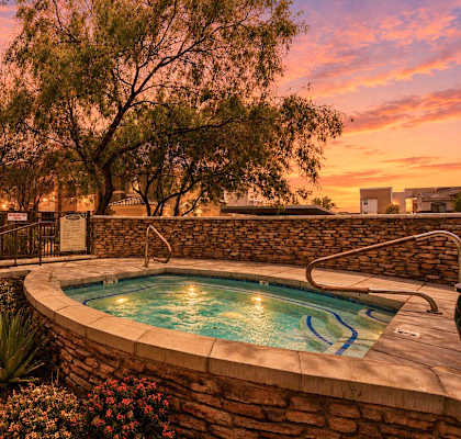 A pool surrounded by a stone wall and plants.