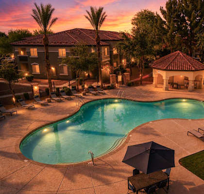 A large outdoor swimming pool surrounded by lounge chairs and umbrellas.