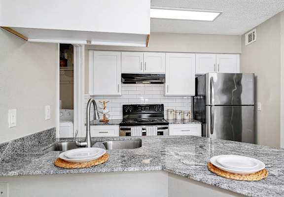 a kitchen with granite counter tops and a stainless steel refrigerator