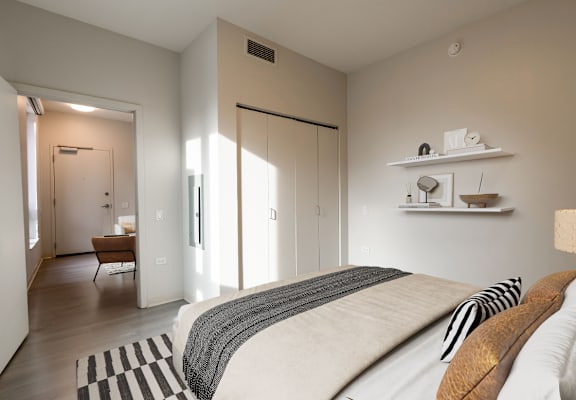 A bedroom with a large bed and a chair in the hallway.