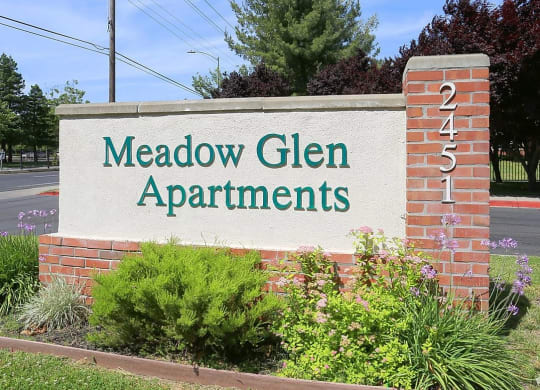 a sign in front of a building that says meadow glen apartments