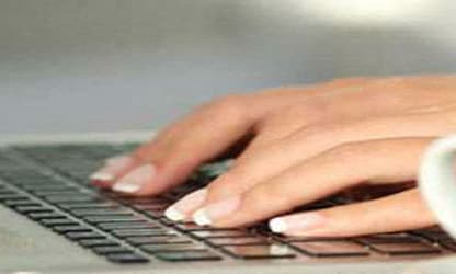 a person typing on a laptop with a cup of coffee