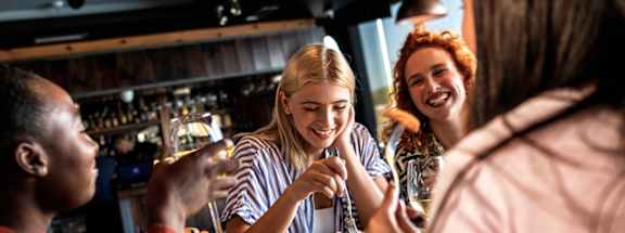 Four people are sitting at a bar, enjoying drinks and conversation.