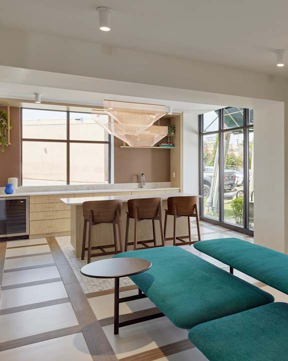 A modern living room with a green sofa and wooden chairs.
