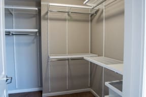 Midtown Sacramento CA Apartments - The Penthouses at Capitol Park - Bedroom Closet With Several Layers of Shelving With Clothing Racks, Tubs for Additional Storage, and Carpet Flooring