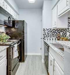 A kitchen with a black refrigerator and white cabinets.