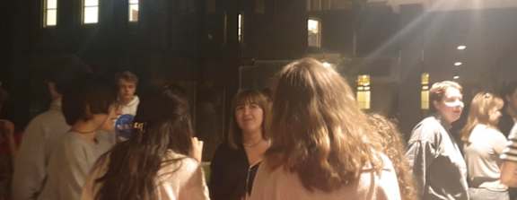 A group of people are standing in a room with a large window.