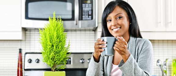 a woman holding a cup of coffee in the kitchen