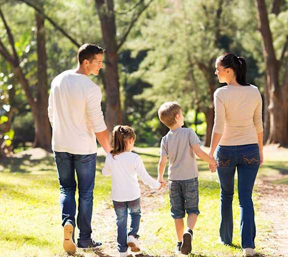 A family of four is walking hand in hand through a park.at Villa Solera, California, 95122