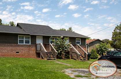 A house with a brick wall and a grey roof with a Universal Living logo in the corner.