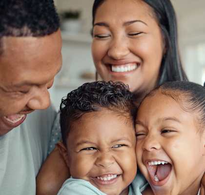 A family of three is hugging and laughing together.