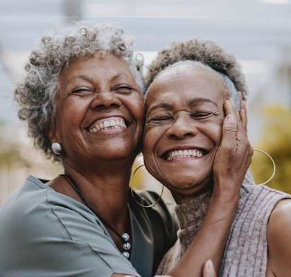 Two women laughing together in an outdoor setting.
