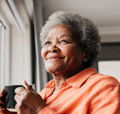 A woman with a cup in her hand is smiling.