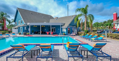 Fusion Apartments Orlando swimming pool with sundeck, blue chairs, and blue clubhouse
