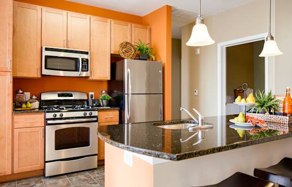 A kitchen with a stove, refrigerator, and microwave.