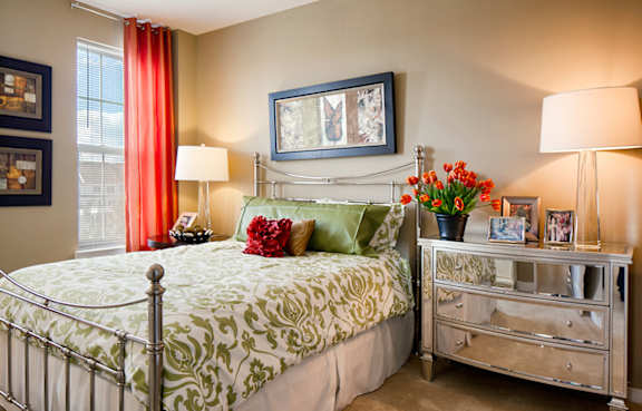 A bedroom with a bed, nightstand, and a painting on the wall.