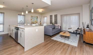 A modern kitchen with a wooden floor and a grey sofa.