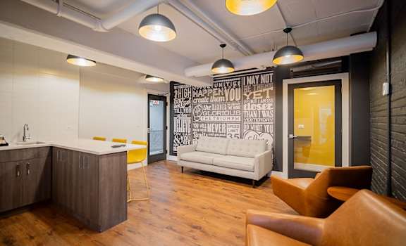 A modern office space with a kitchen area and a couch.
