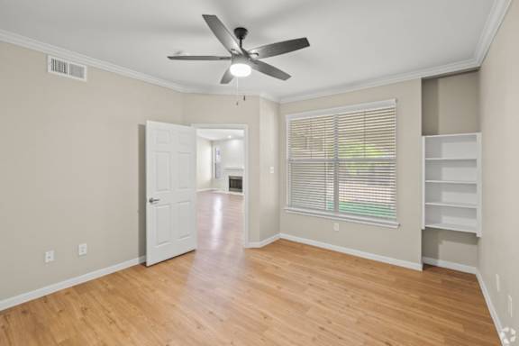 A room with a ceiling fan and wooden flooring.