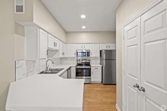 A kitchen with white cabinets and appliances.