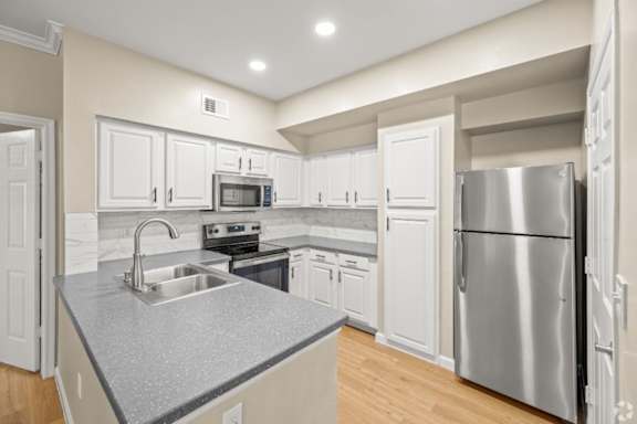 A kitchen with a stainless steel refrigerator and a granite countertop.