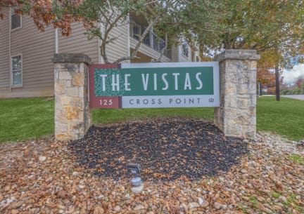 A sign that says "The Vistas" stands in front of a building.
